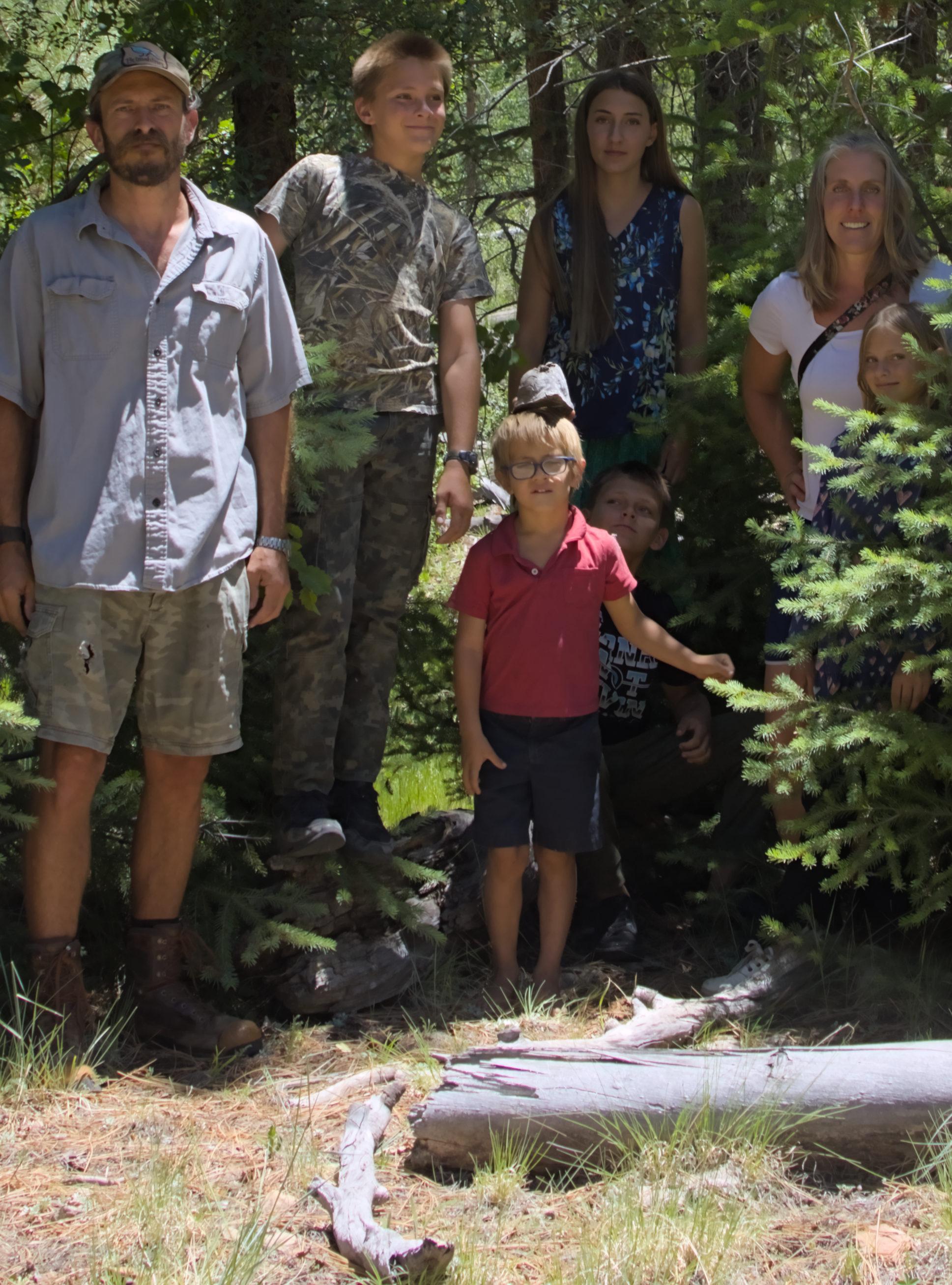 The Brimshiner family standing among the pines on an Arizona mountain.